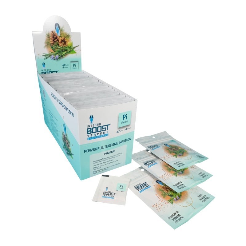 Integra Boost Terpene Essentials Pineeni 67g pakkaus ja kosteusilmaisinkortti, asetettuna yrttien viereen ilmatiiviissä astiassa, jossa näkyy havun oksia ja käpyjä taustalla.
