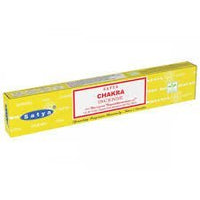 Kuva Satya Chakra suitsuketikuista savuamassa tummalla taustalla, taustalla heikosti näkyvissä chakrasymboleja edustava grafiikka